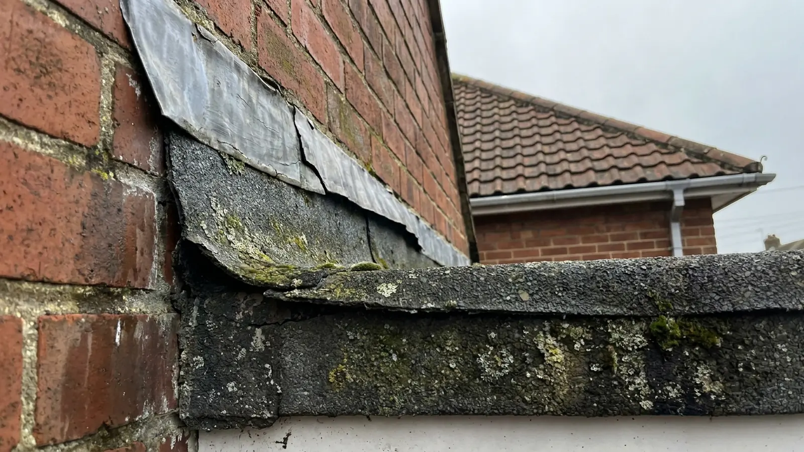 A flat roof upstand pulling away from a wall