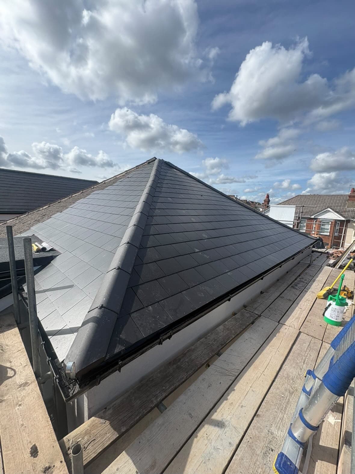 A finished anthracite tiled roof tied into the flat roof of the section below it